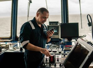 Marine navigational officer is changing speed ship or vessel during navigation watch. He speaks with engine room by walkie-talkie uhf radio